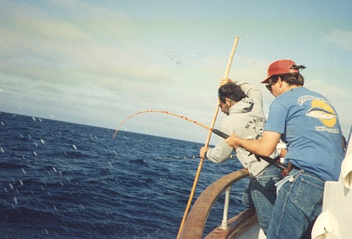 Peter holding a bent rod while Capt. Ron reaches down with a gaff