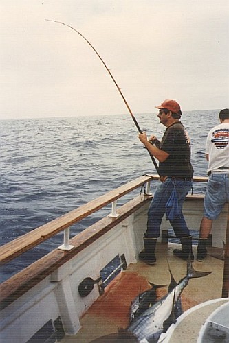 Peter holding a bent rod, with a sack of tuna in the foreground